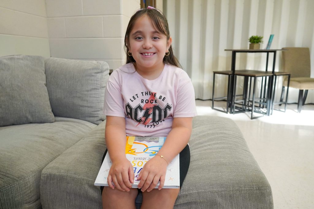 Analeya sitting with a book on her lap, smiling. 